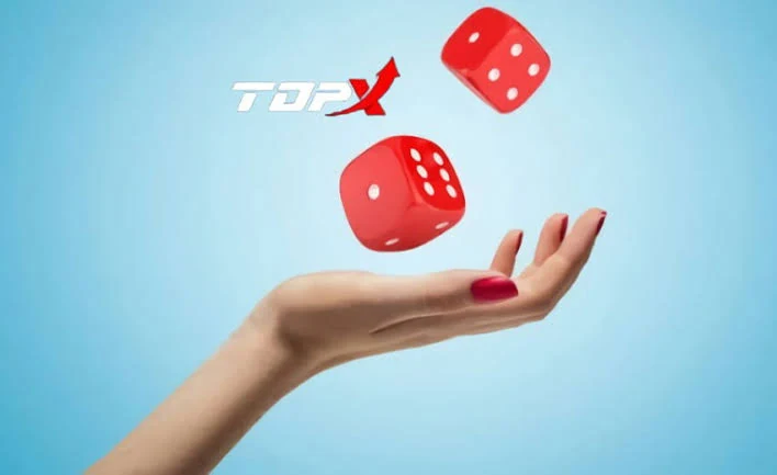 Mão feminina lançando dois dados vermelhos sobre fundo azul claro, imagem de divulgação da TopX